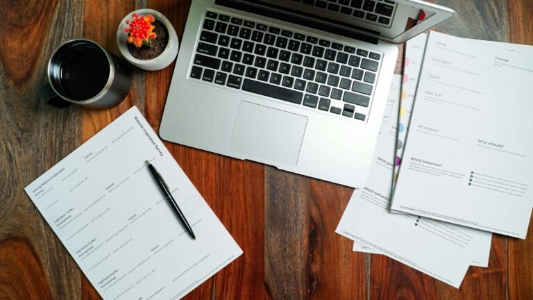 Modern desk workspace with a laptop, coffee, and printed paperwork for creating a standard business quotation format.