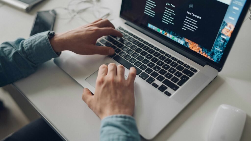Close up view of hands typing on a laptop screen detailing how to make money with artificial intelligence via freelancing and content creation