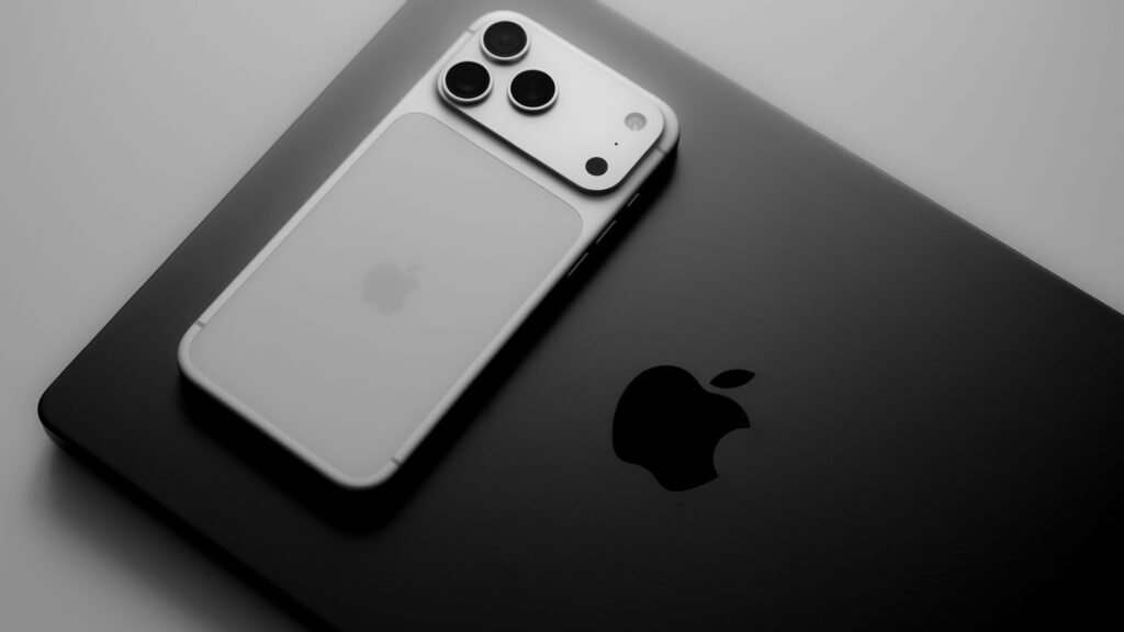 Silver iPhone 18 resting on a dark MacBook top for when does iphone 18 come out article