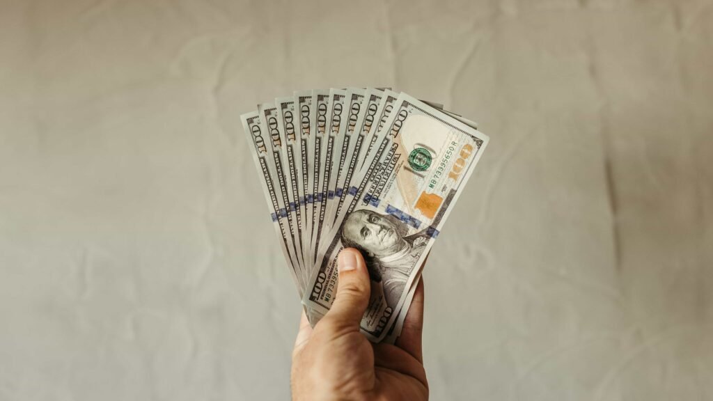 Hand holding US dollar bills representing creator monetization in threads app vs twitter comparison